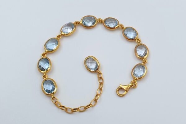 Bracciale dorato con topazi blu ovali sfaccettati. BH0040